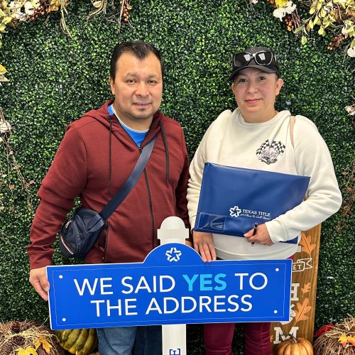 A couple holding a sign saying they said yes to the address